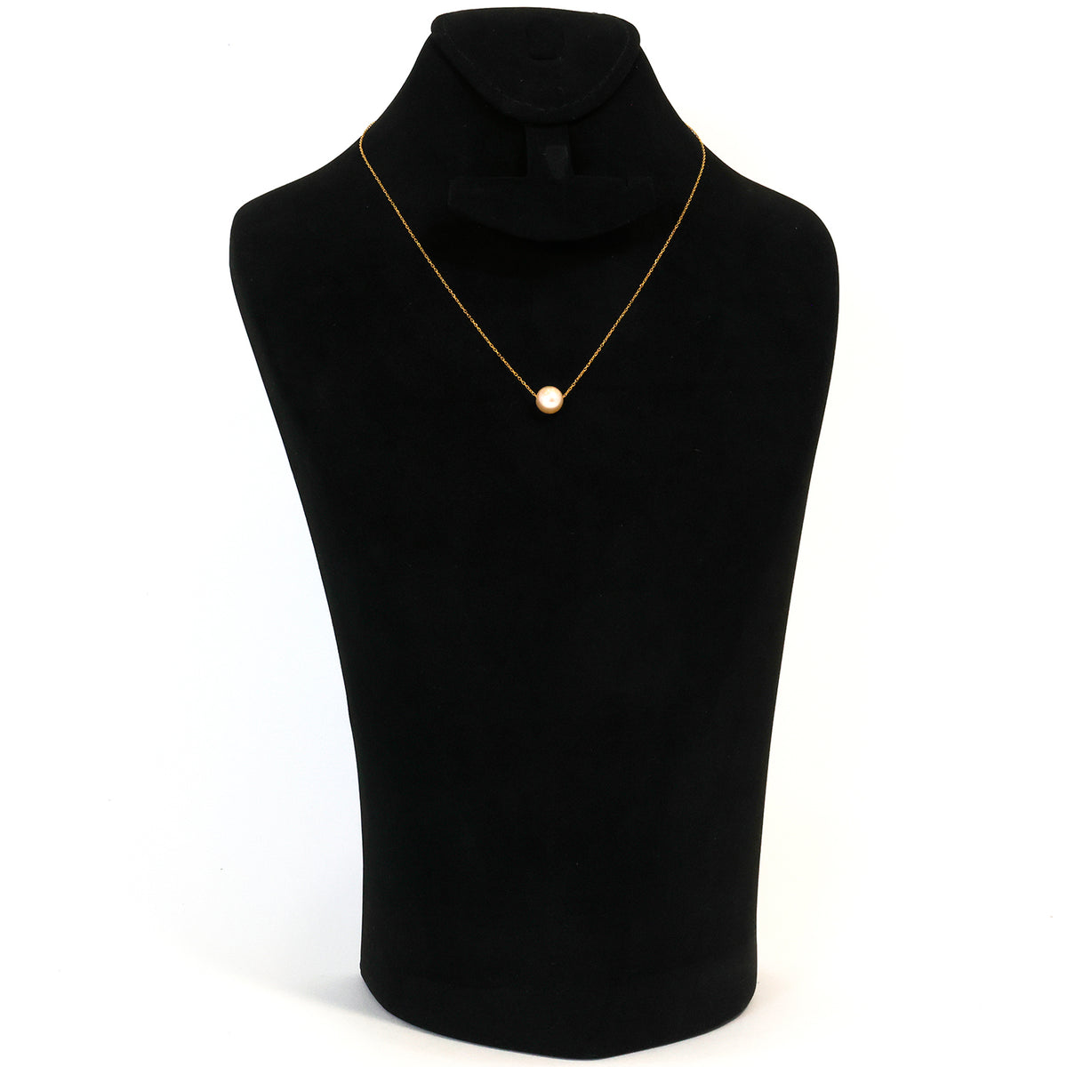 Black mannequin wearing a gold necklace with a pearl pendant on a white background