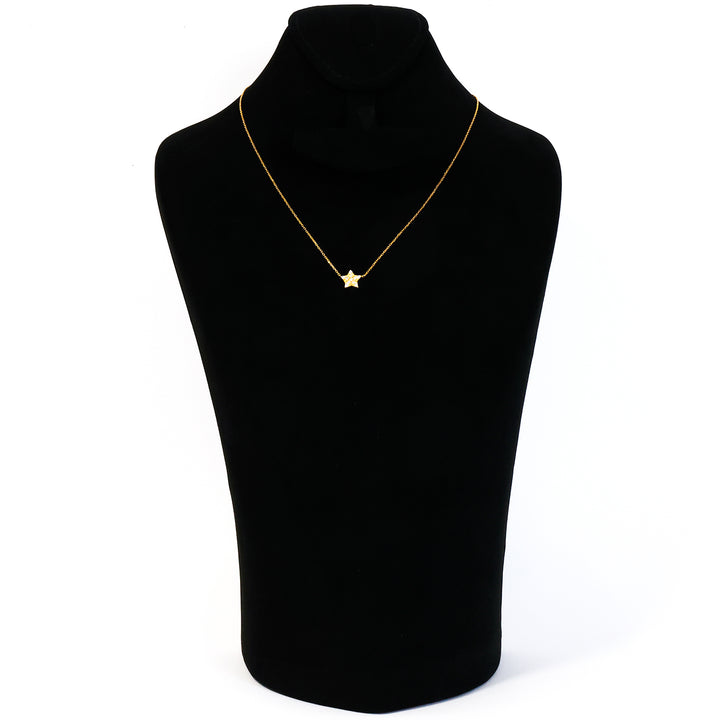 Gold star necklace on a black mannequin bust against a white background