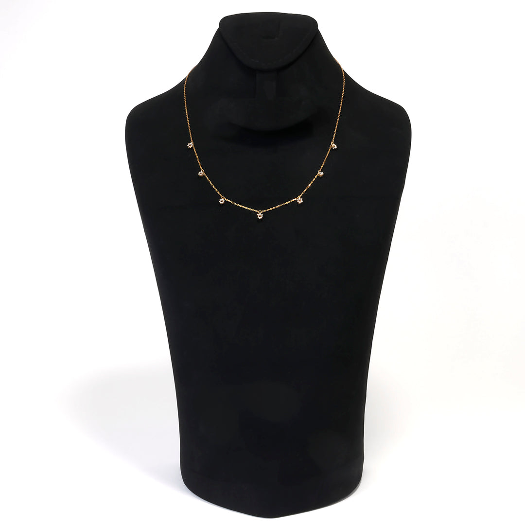 Gold necklace on a black mannequin bust against a white background