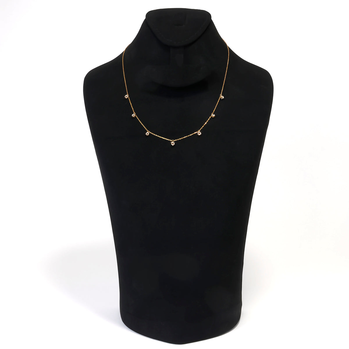 Gold necklace on a black mannequin bust against a white background