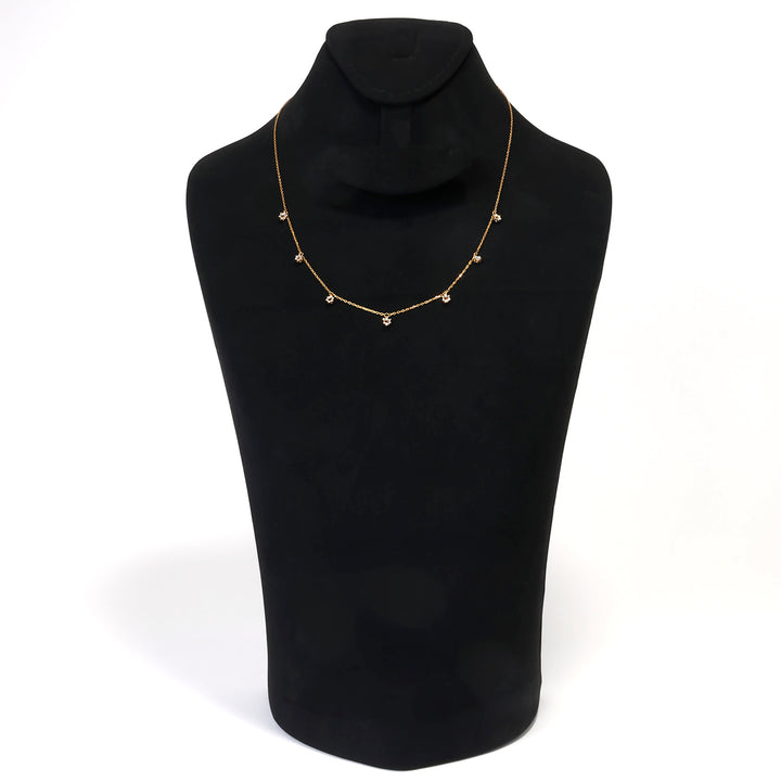 Gold necklace on a black mannequin bust against a white background