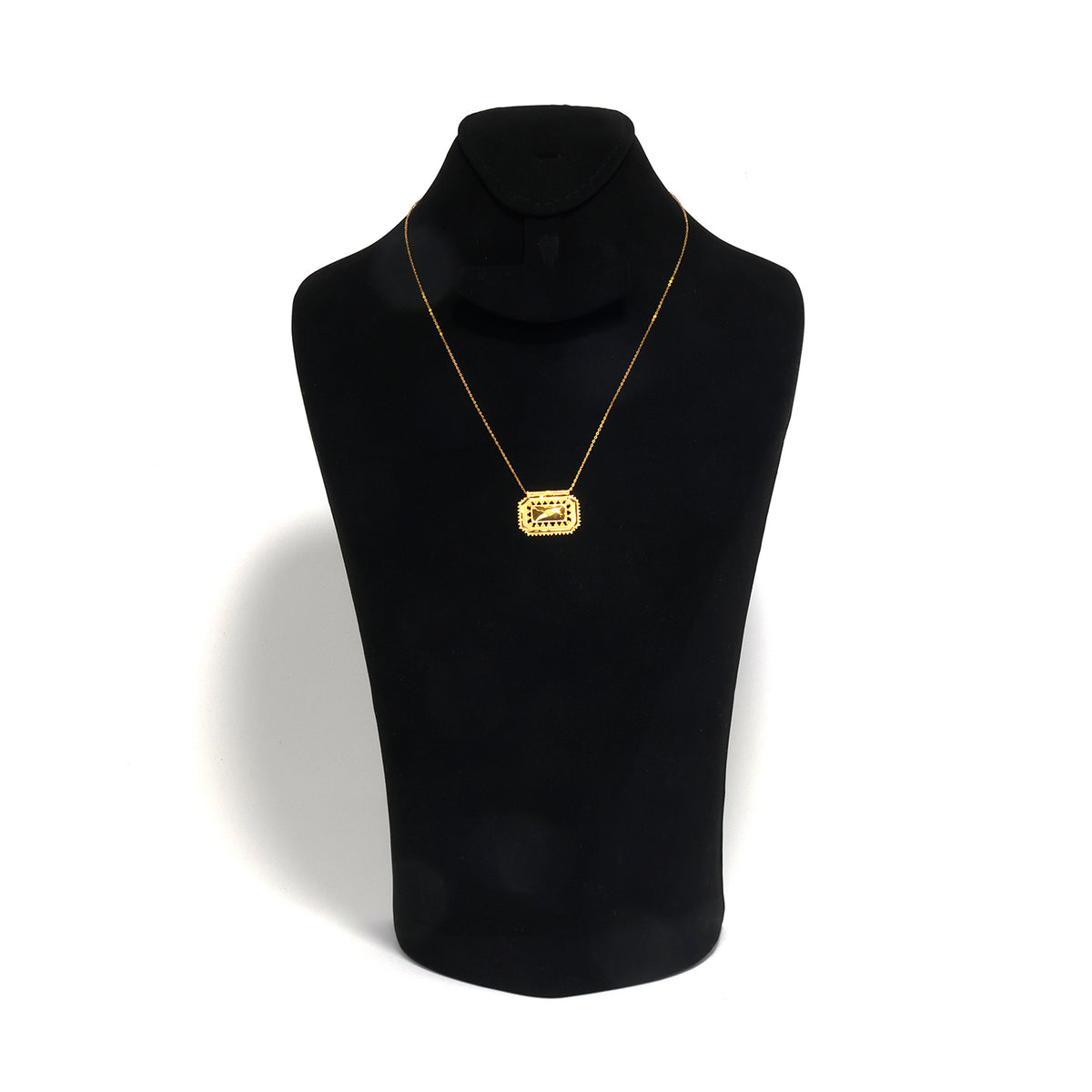 Gold necklace on a black mannequin bust against a white background