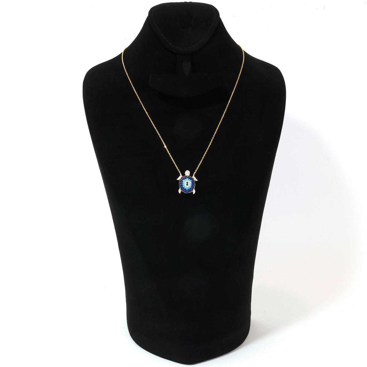 Gold necklace with a blue pendant on a black mannequin bust against a white background