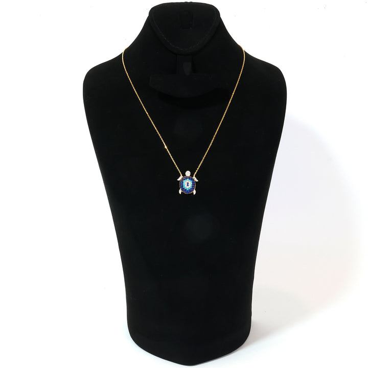 Gold necklace with a blue pendant on a black mannequin bust against a white background