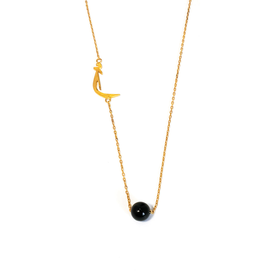 Gold necklace with a black bead and crescent moon pendant on a white background