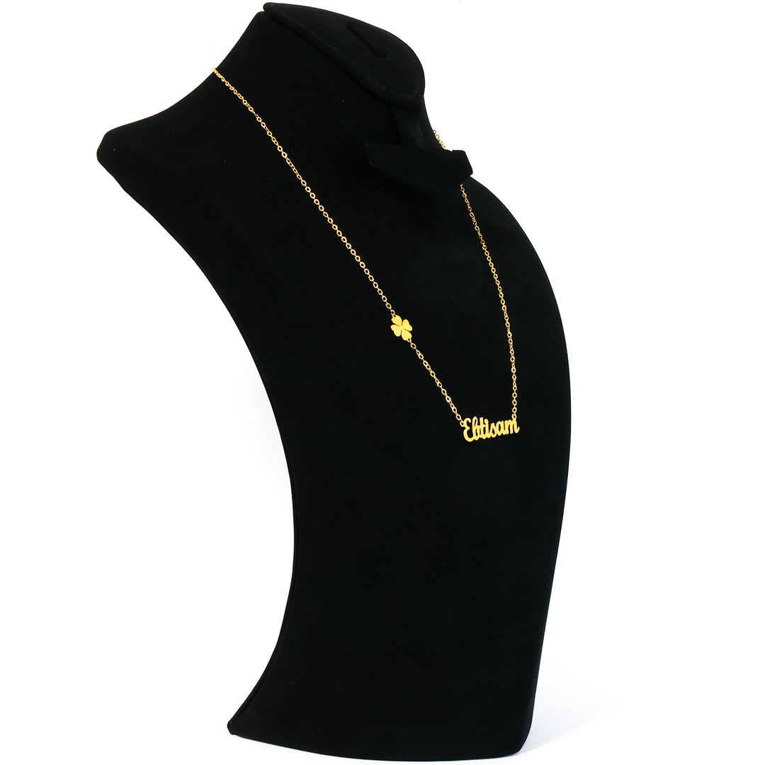 Gold necklace with a clover pendant on a black mannequin bust.