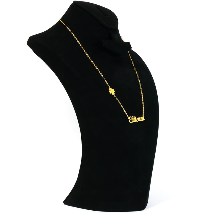 Gold necklace with a clover pendant on a black mannequin bust.