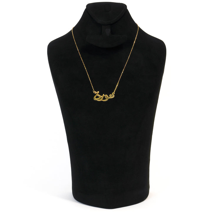 Gold necklace on a black mannequin bust against a white background