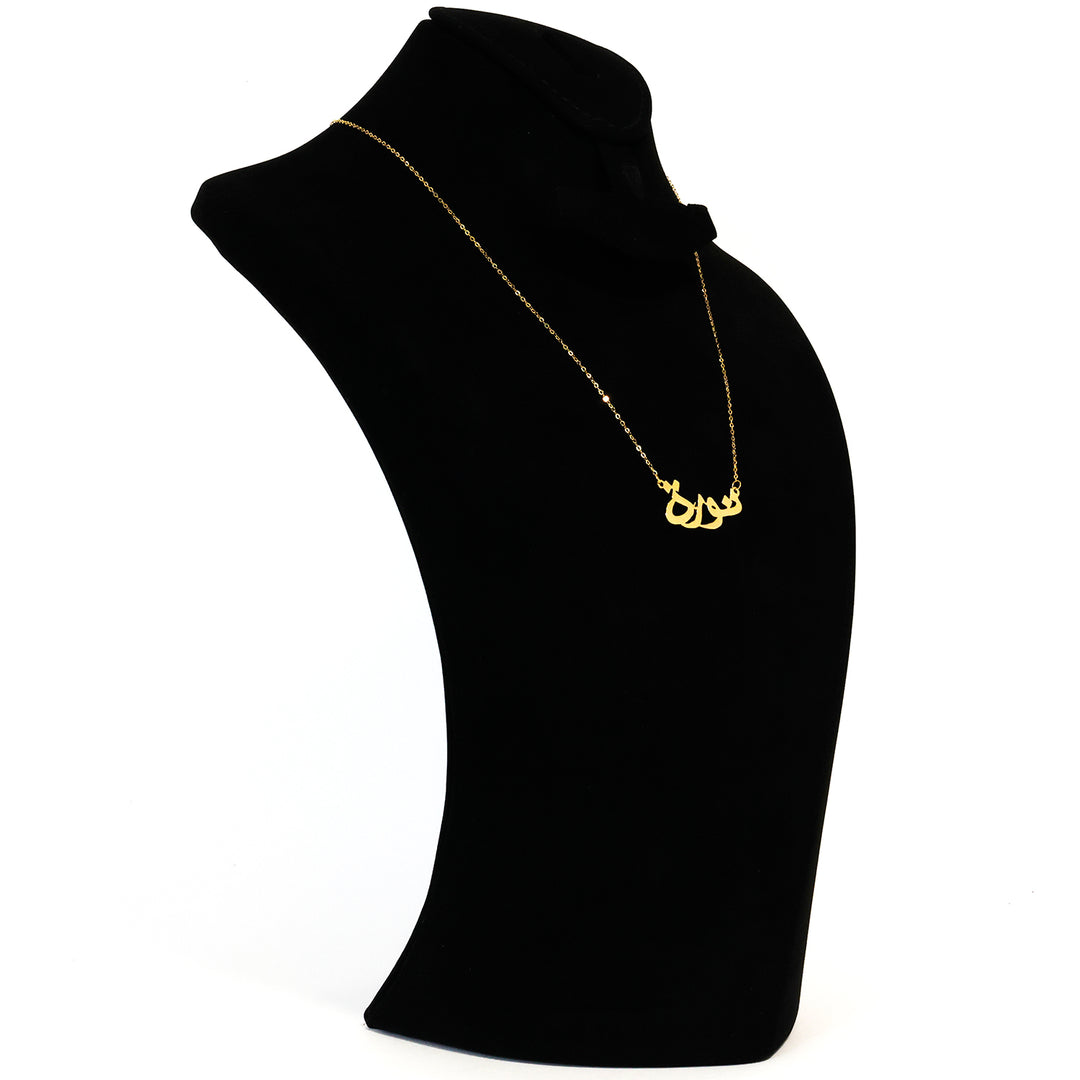 Gold necklace on a black mannequin bust against a white background