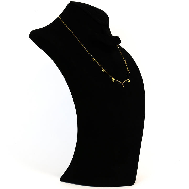 Gold necklace on a black mannequin bust against a white background