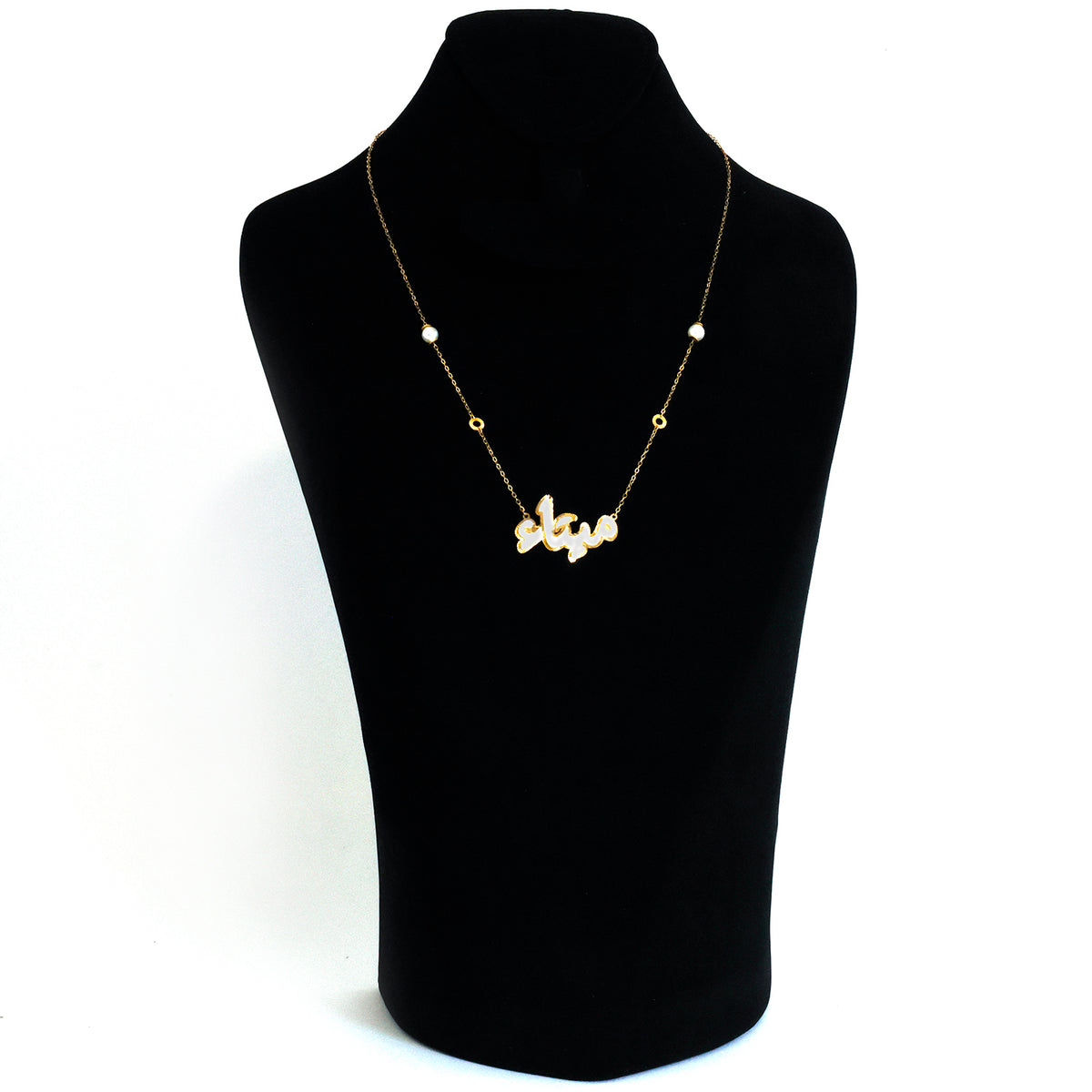 Gold necklace on a black mannequin bust against a white background