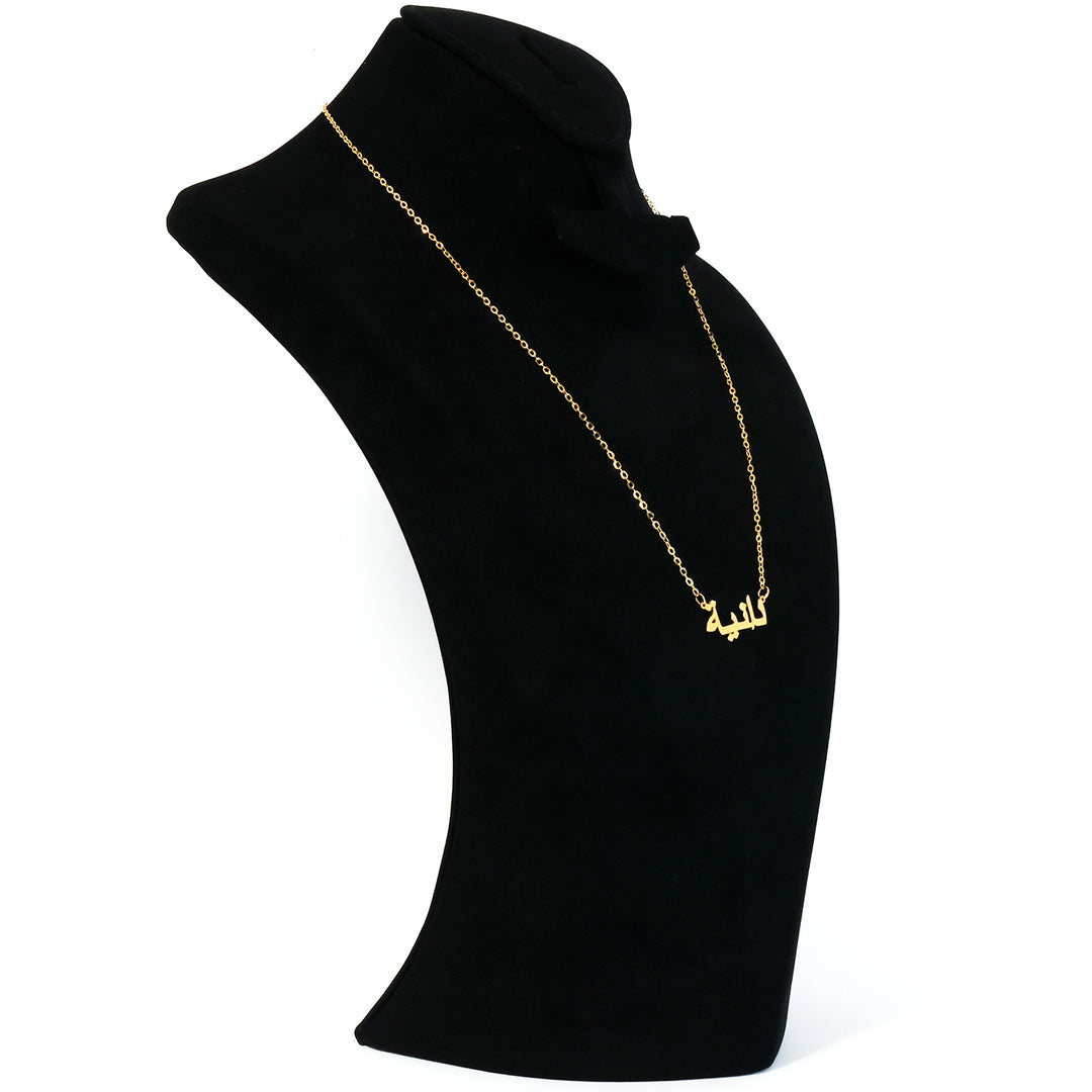 Gold necklace on a black mannequin bust against a white background