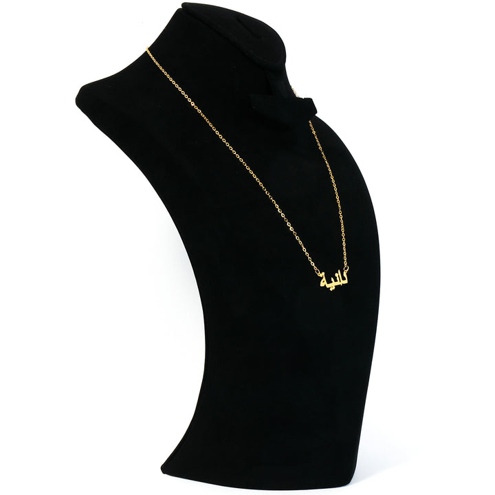 Gold necklace on a black mannequin bust against a white background