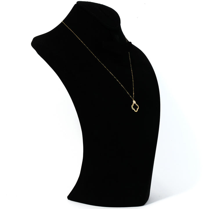 Gold necklace on a black mannequin bust against a white background