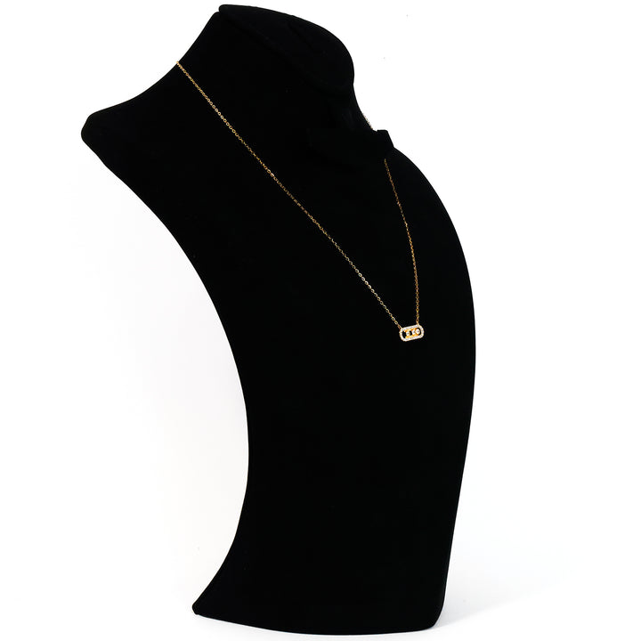 Gold necklace on a black mannequin bust against a white background