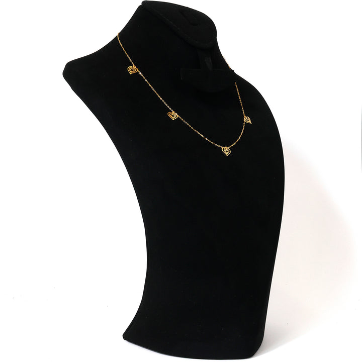 Gold necklace on a black mannequin bust against a white background