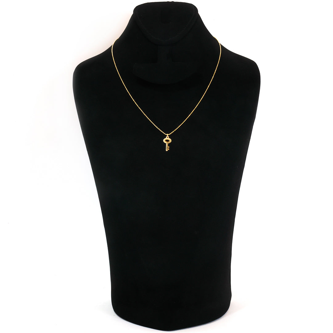 A delicate gold necklace with a small key pendant, displayed on a black velvet jewelry bust against a plain white background.
