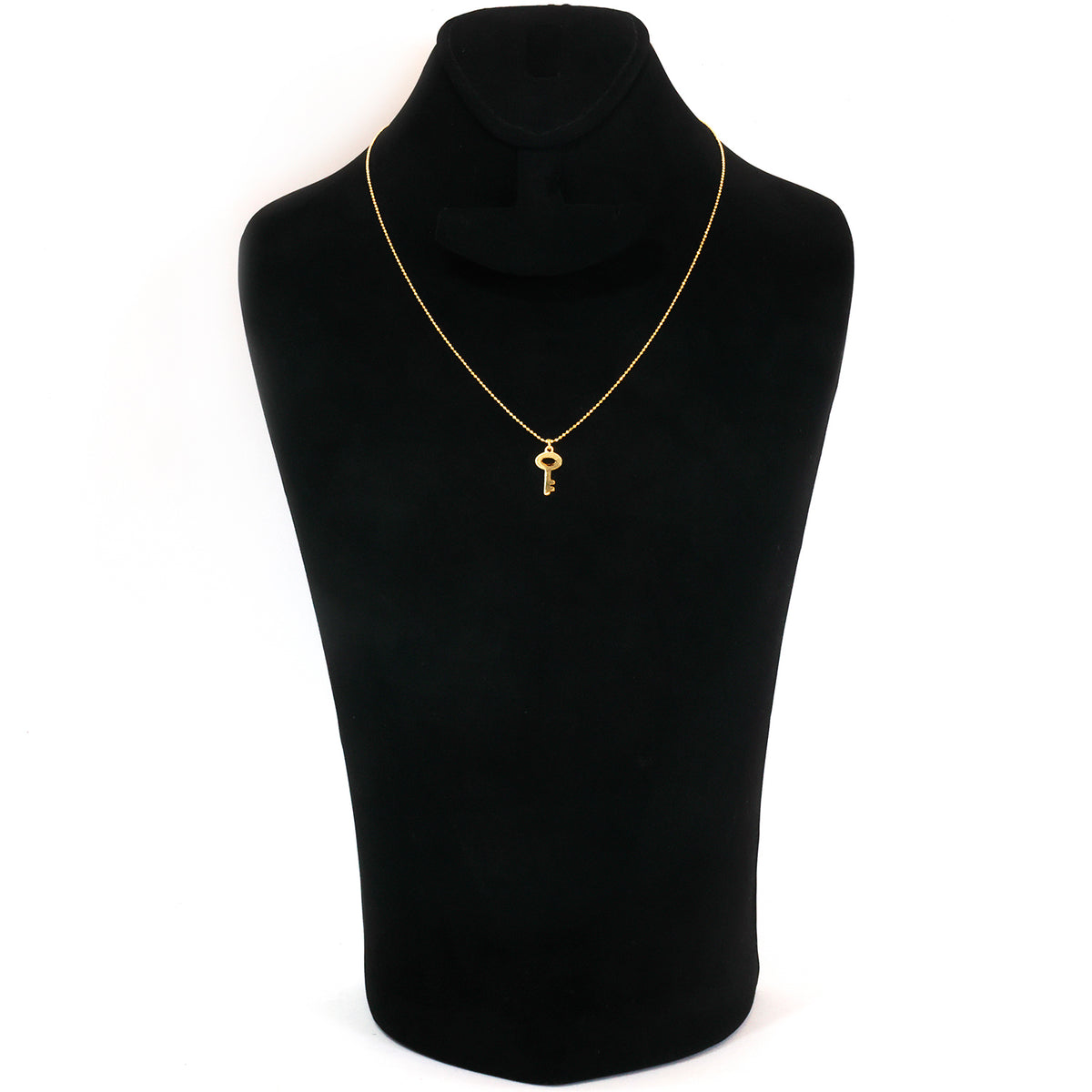 A delicate gold necklace with a small key pendant, displayed on a black velvet jewelry bust against a plain white background.