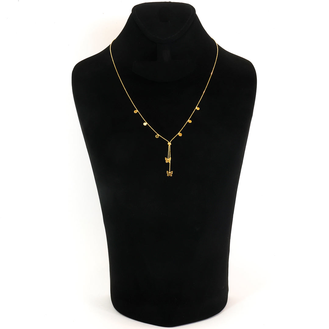 A delicate gold necklace displayed on a black jewelry bust against a white background. The necklace features a fine chain with small gold beads and a central pendant with a vertical bar and a small hanging charm.