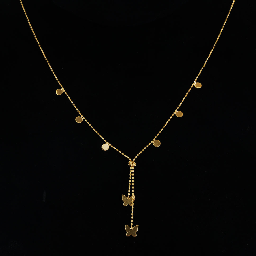 A delicate gold Y-necklace with small flat circular disc charms on the chain and two butterfly pendants hanging from the center, displayed on a black background.