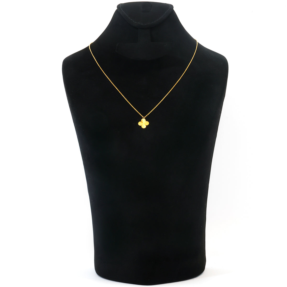 A gold necklace with a small four-leaf clover pendant displayed on a black jewelry bust against a white background.