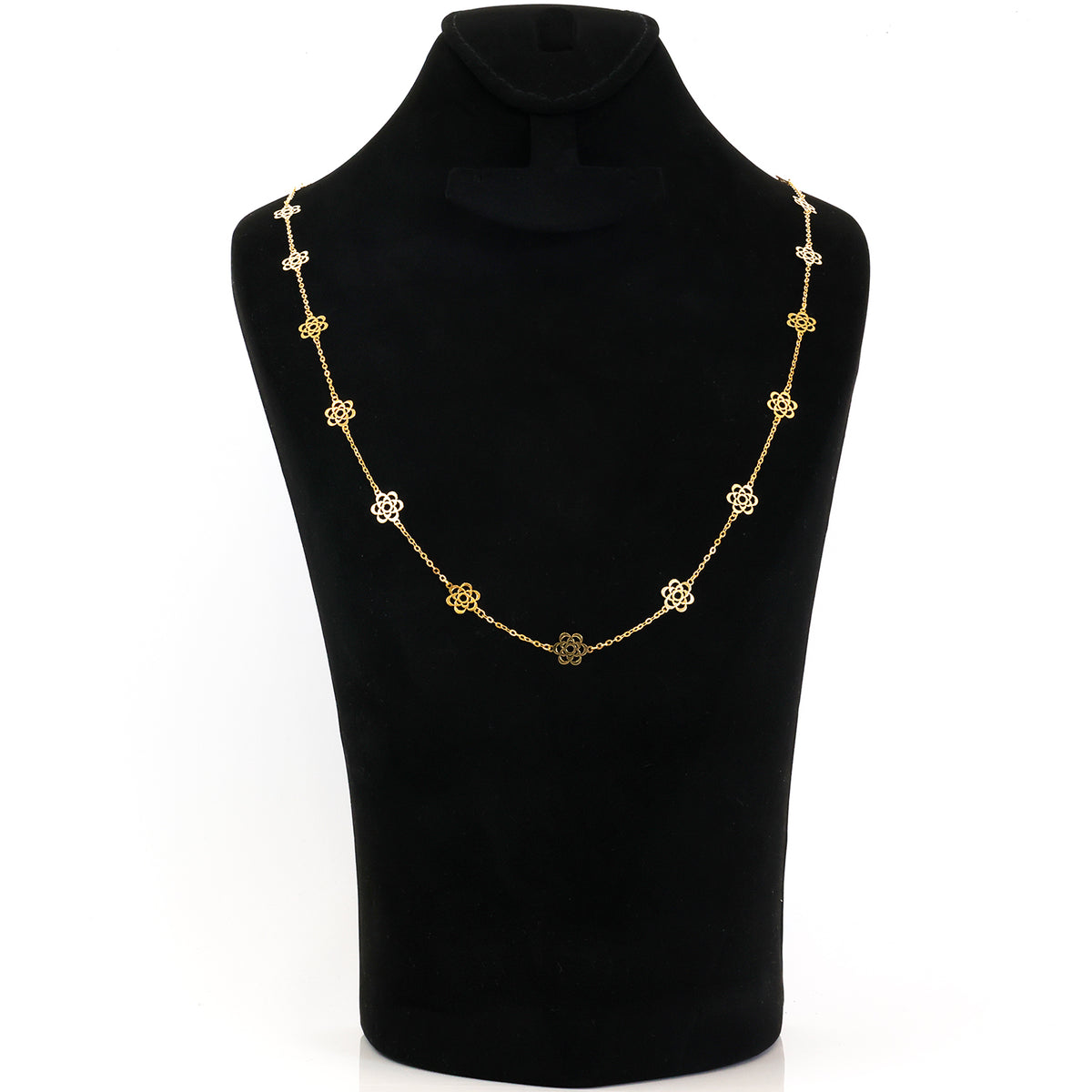 A gold chain necklace with repeating flower-shaped links, displayed on a black velvet jewelry bust against a white background.