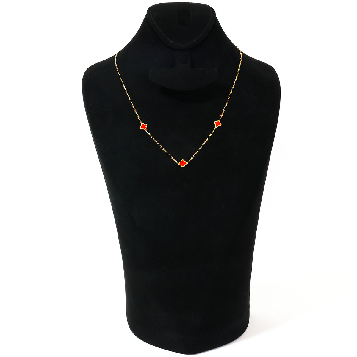 A delicate gold chain necklace with three small red diamond-shaped stones, displayed on a black velvet jewelry bust against a white background.