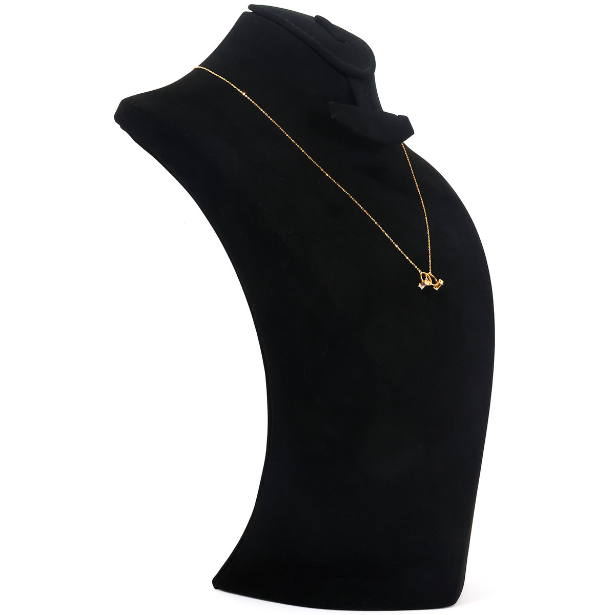 A delicate gold chain necklace with a small gold pendant displayed on a black jewelry bust against a white background.