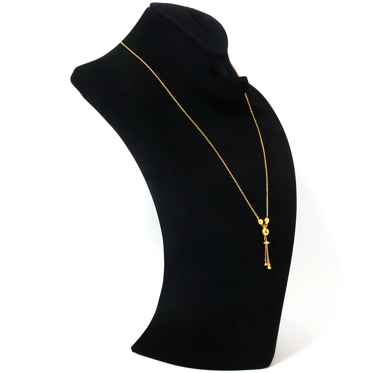 A delicate gold chain necklace with a small ornate pendant and dangling charms, displayed on a black jewelry bust against a white background.