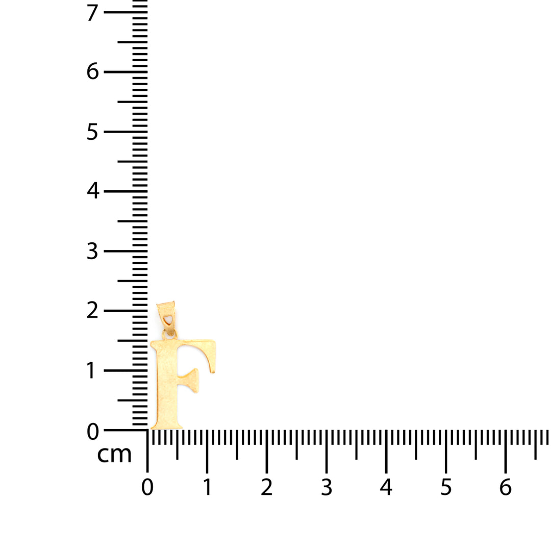 A gold initial pendant shaped like the letter 'F' is shown next to a centimeter ruler to indicate its size, on a plain white background.