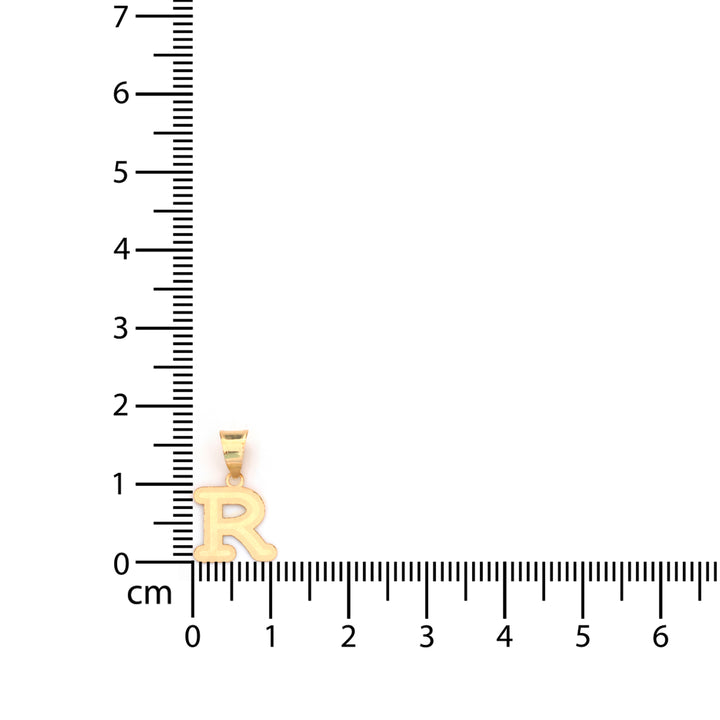 Gold pendant next to a ruler on a white background