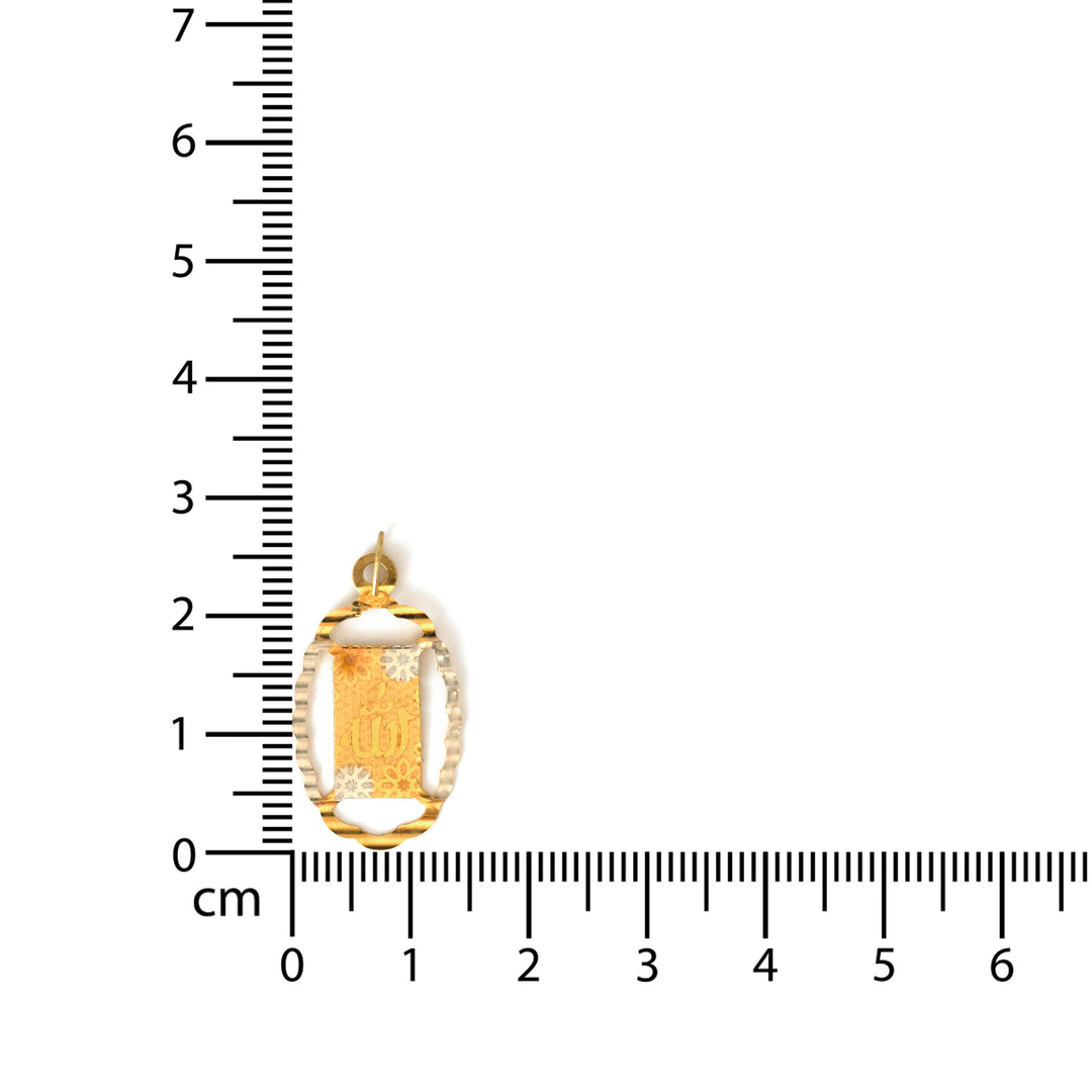 Gold pendant with a ruler for scale on a white background