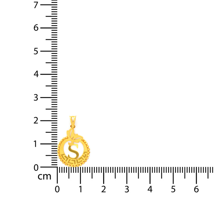 Gold pendant with 'S' design next to a ruler on a white background