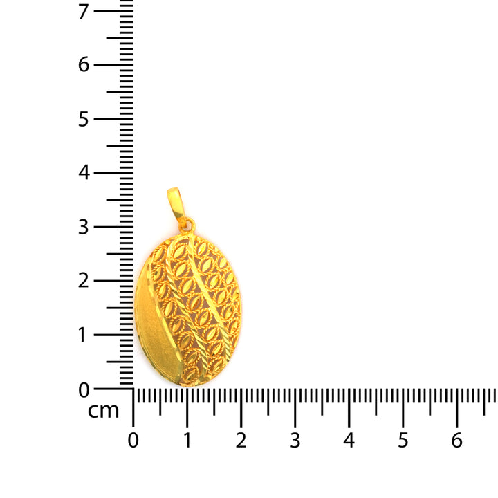 Gold pendant with intricate design on a white background with a ruler for scale.
