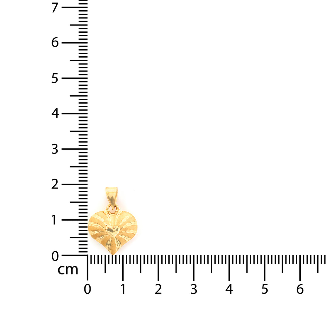 Gold heart-shaped pendant next to a ruler on a white background