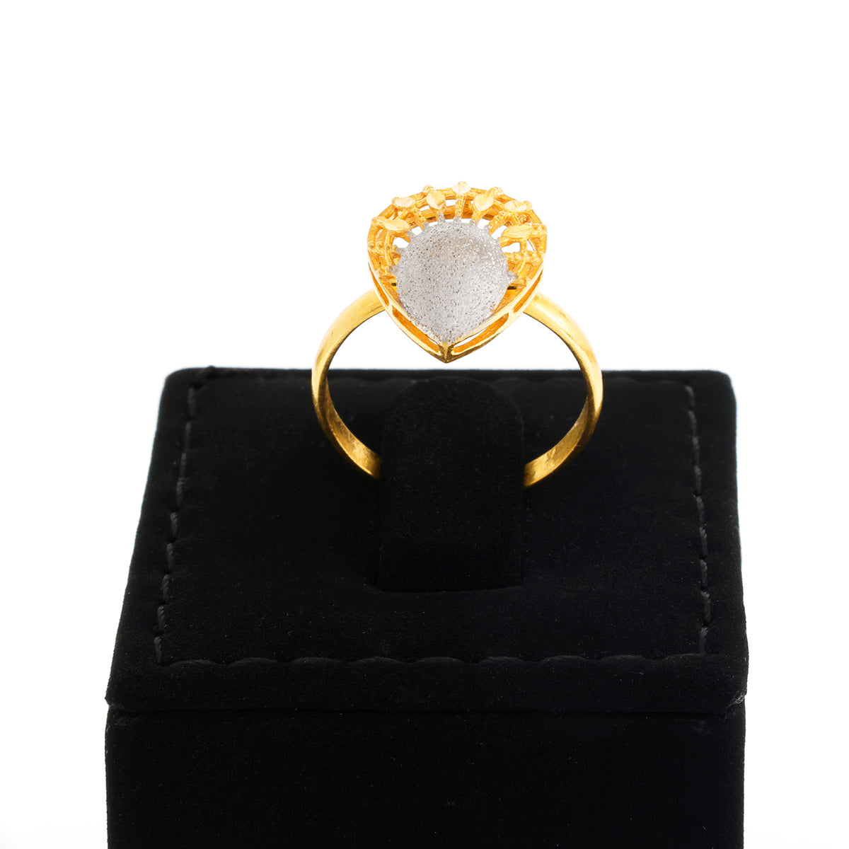 Gold ring with a heart-shaped stone on a black velvet stand