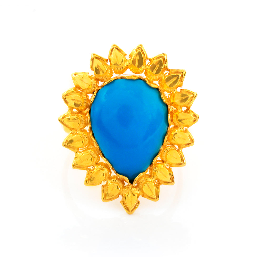 Gold ring with a blue teardrop-shaped gemstone on a white background