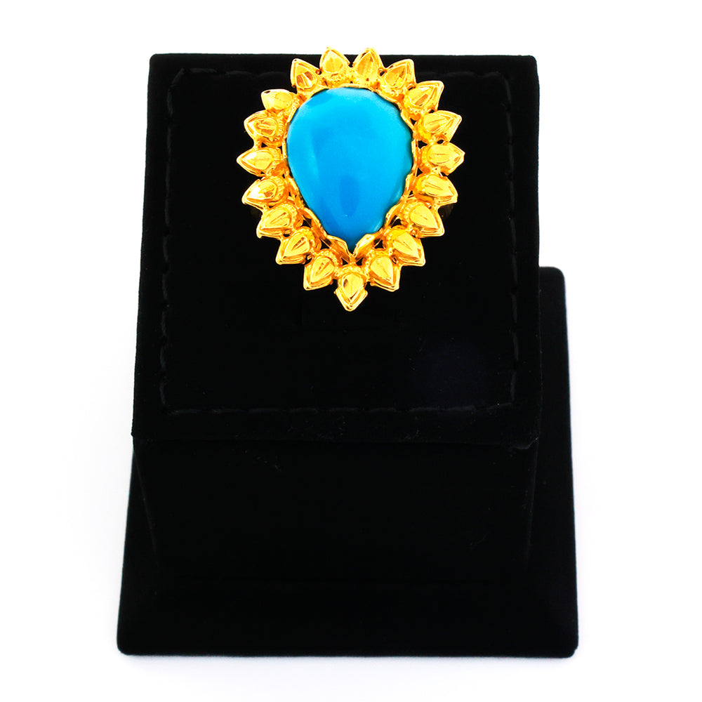Gold brooch with a blue gemstone on a black stand