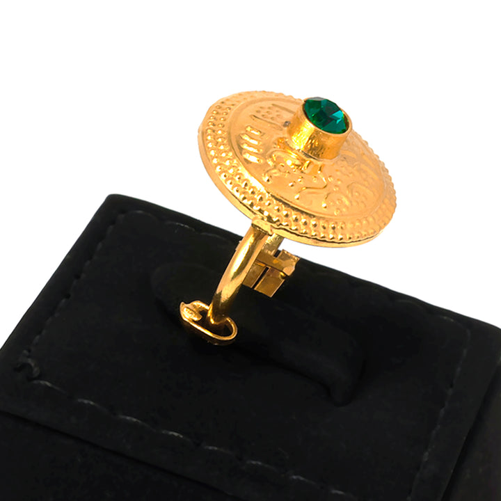 Gold ring with a green gemstone on a black cushion