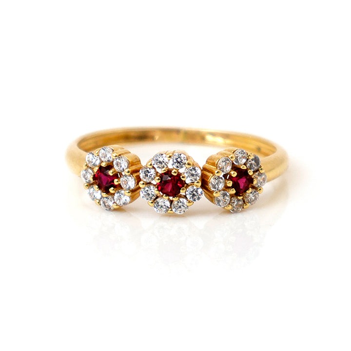 Gold ring with red gemstones and diamond accents on a white background