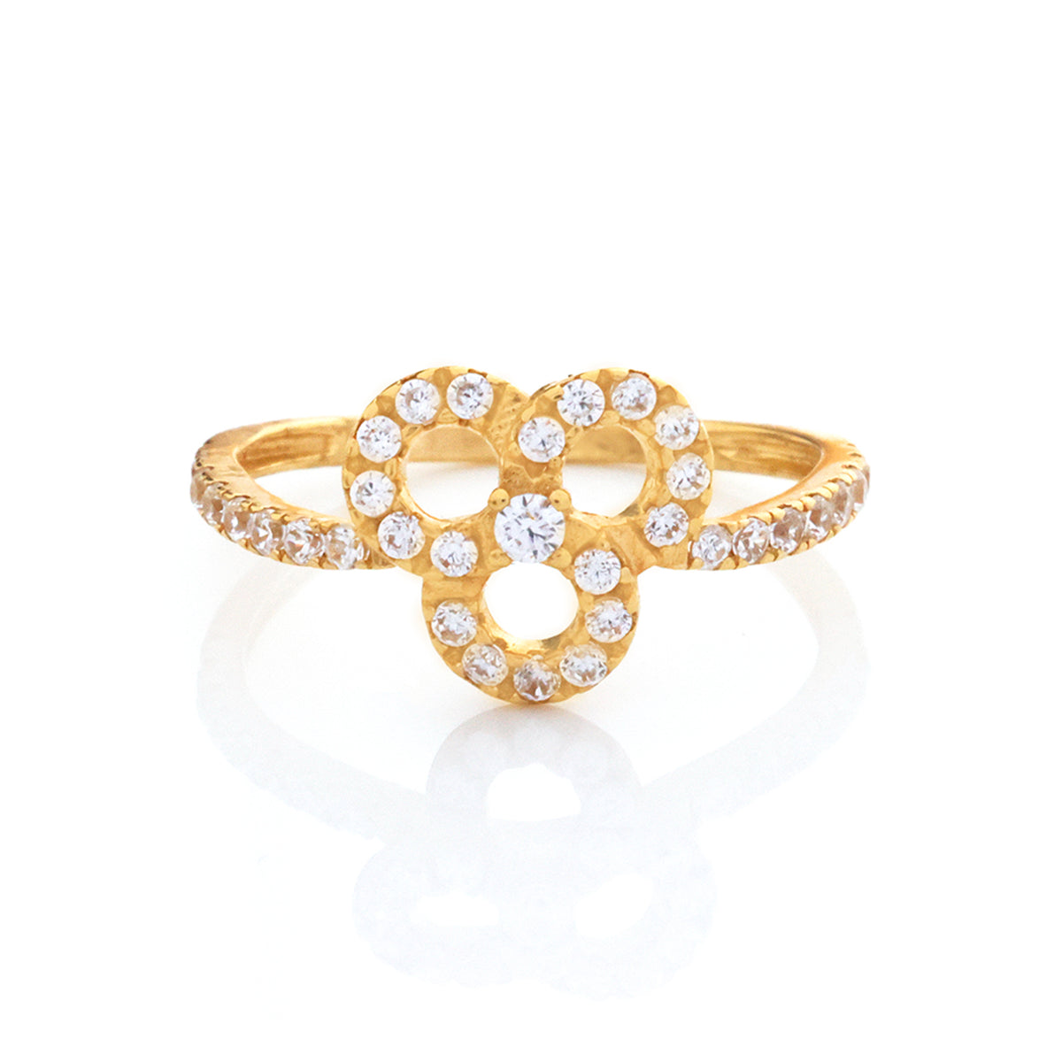 A gold ring featuring a central openwork floral or heart-shaped motif set with clear round gemstones, with additional small stones along the band, shown on a white background with a soft reflection.
