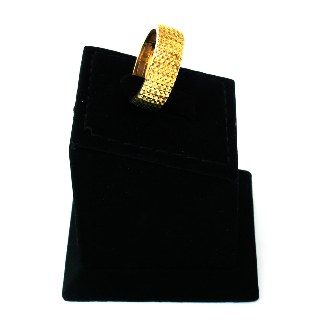 Gold bracelet on a black velvet stand against a white background