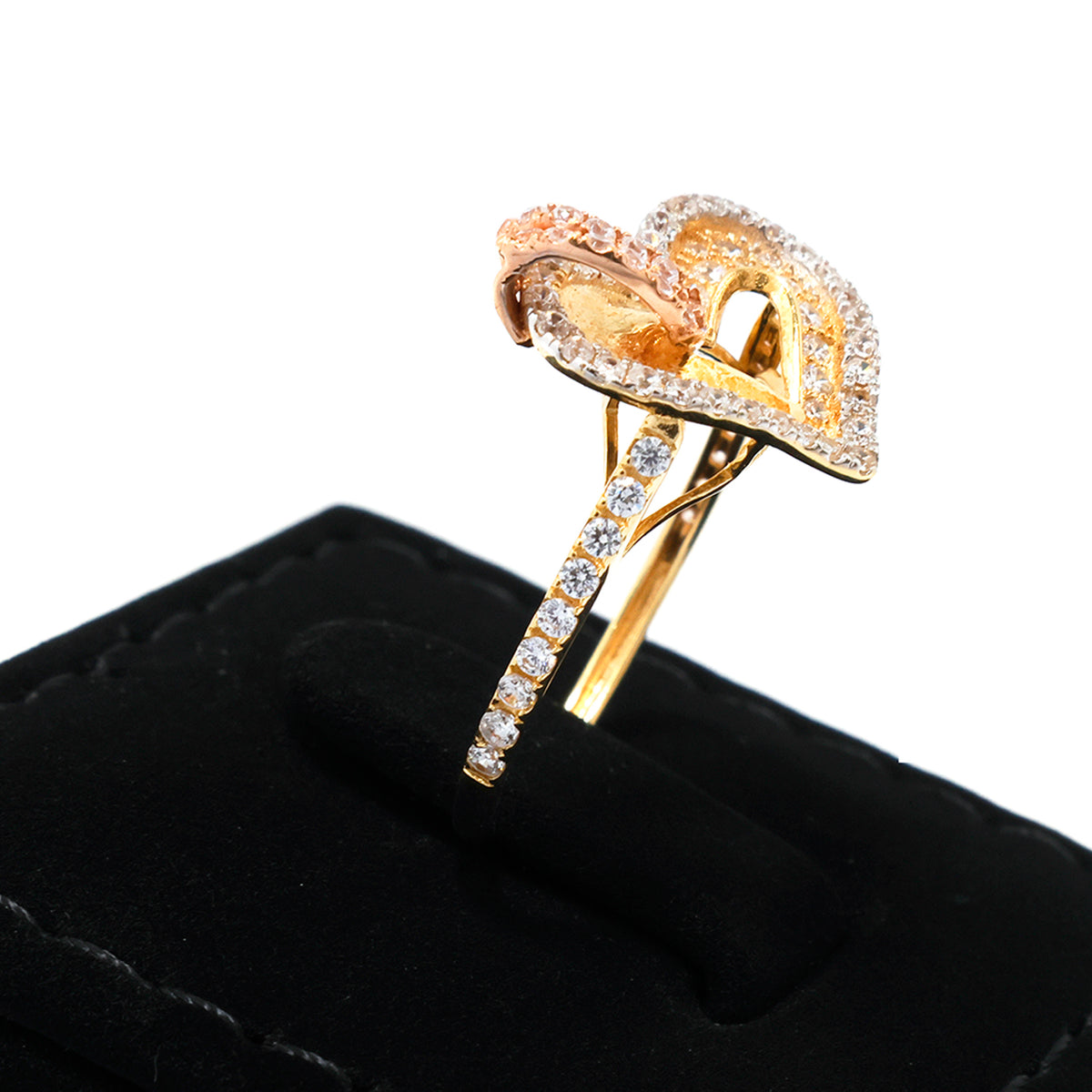 Gold ring with diamond accents on a black cushion against a white background