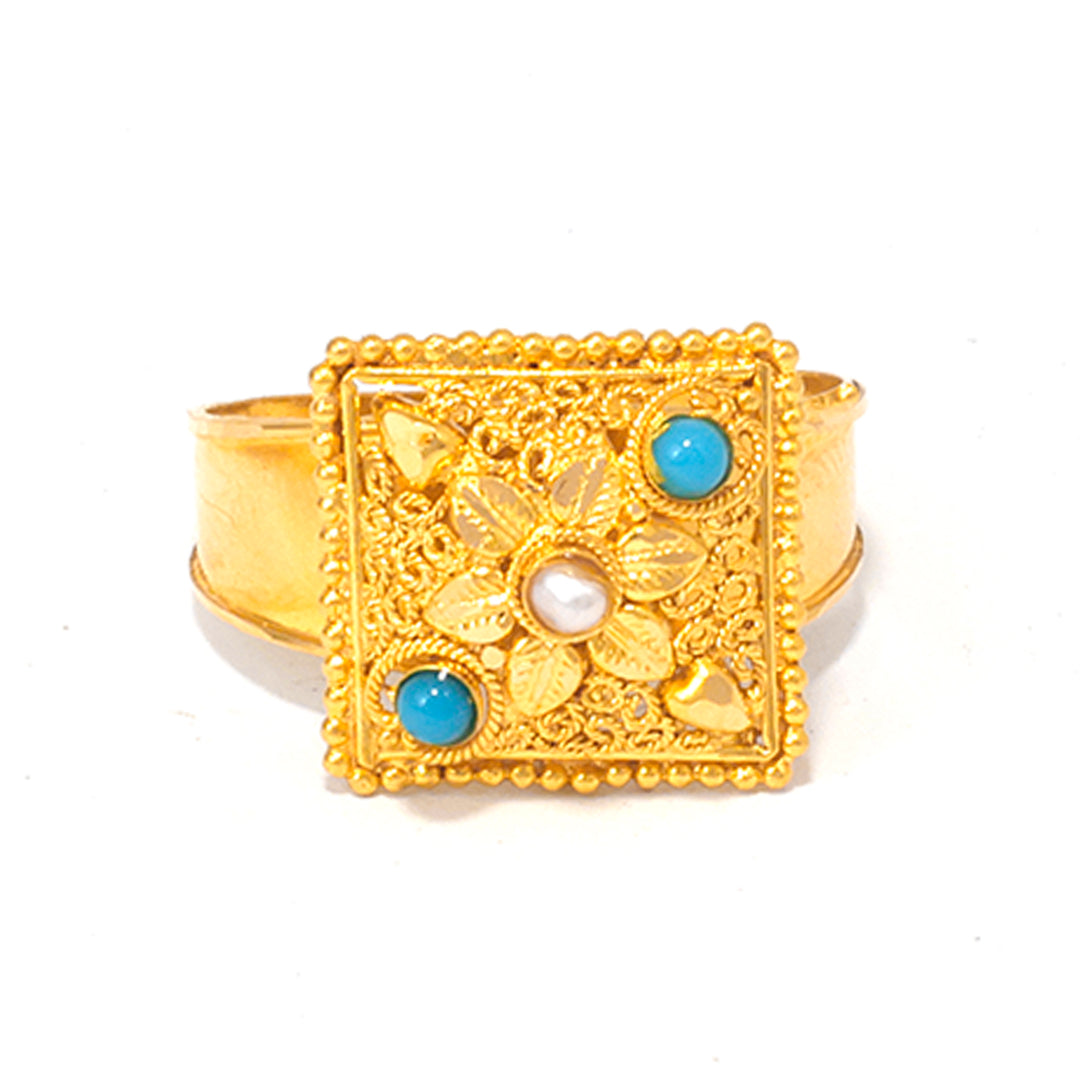 Gold ring with floral design and blue gemstones on a white background