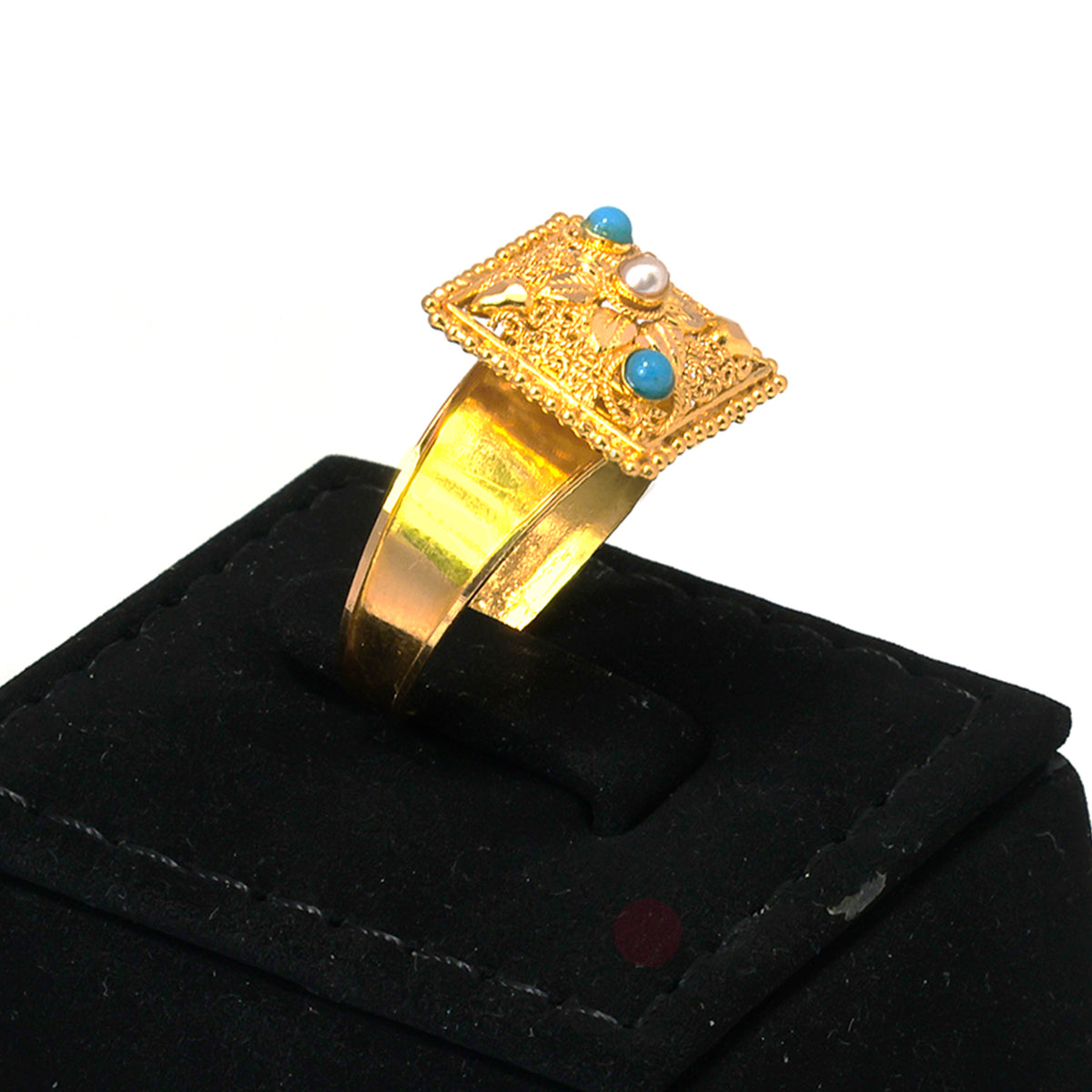 Gold ring with gemstones on a black stand against a white background