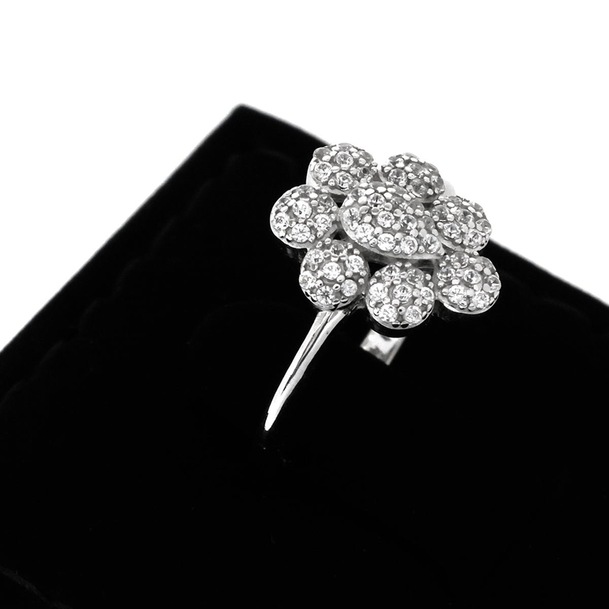 Silver flower-shaped brooch with clear gemstones on a black background
