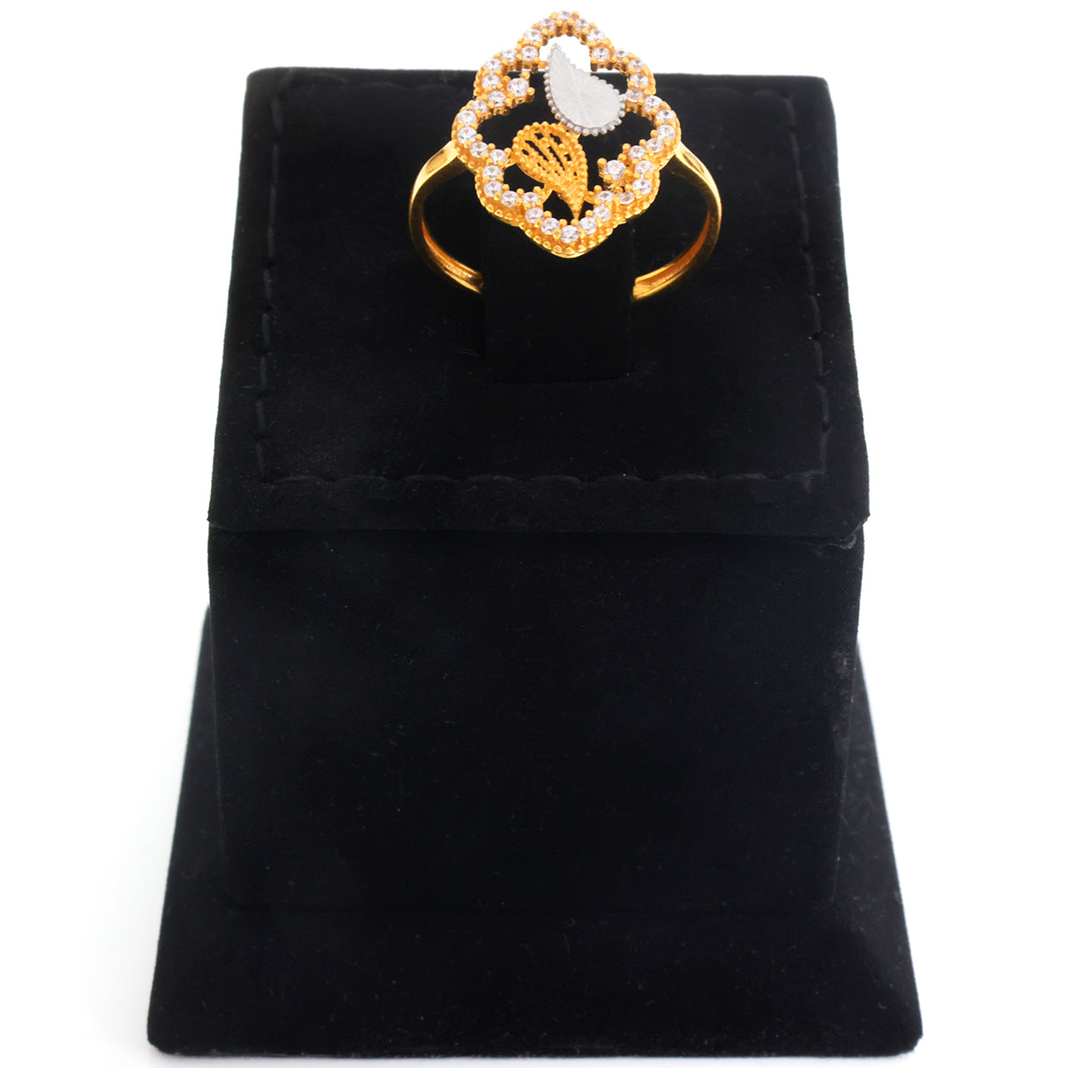 A gold ring with a decorative floral or clover-like top set with small clear stones and a central white stone, displayed on a black velvet ring box against a white background.