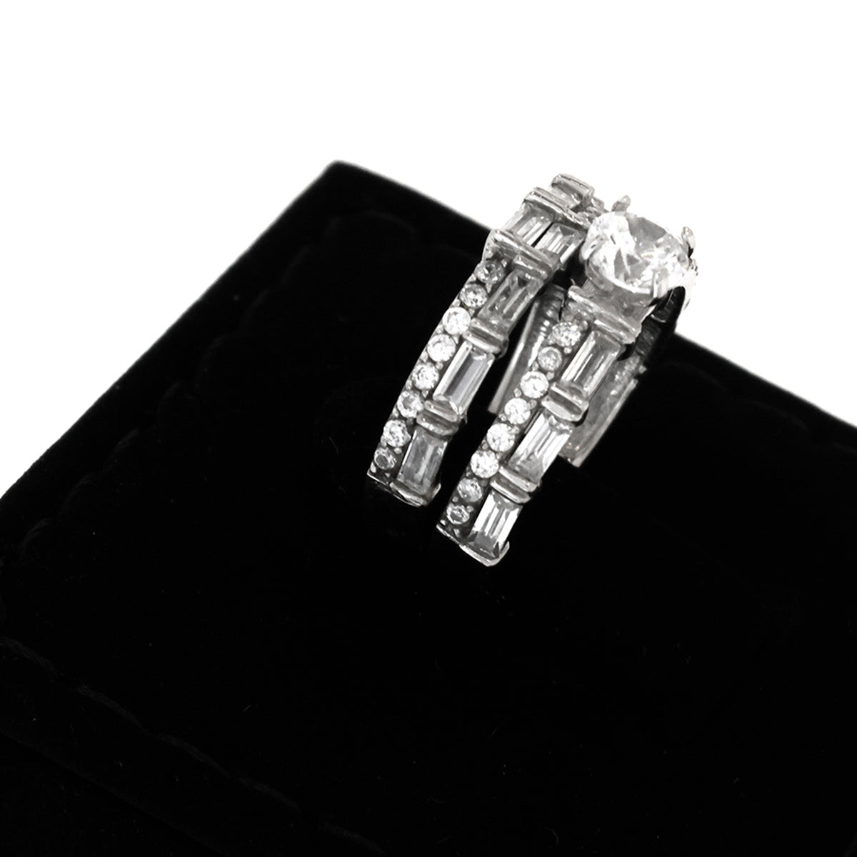 Pair of silver hoop earrings with clear gemstones on a black velvet background