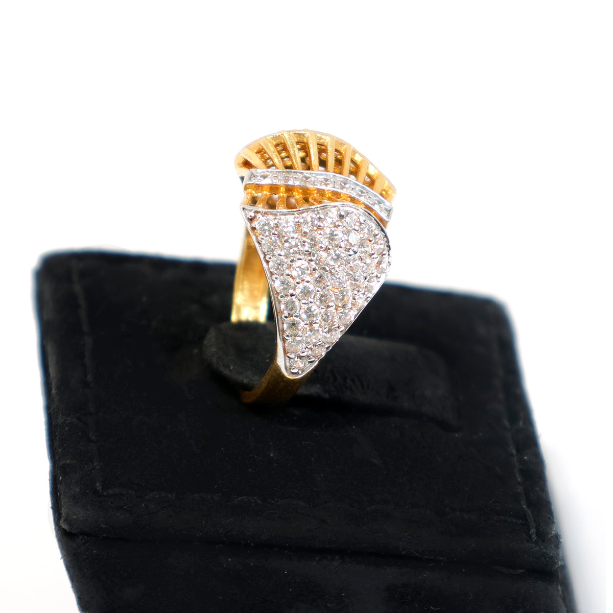 Gold and diamond ring on a black cushion with a white background