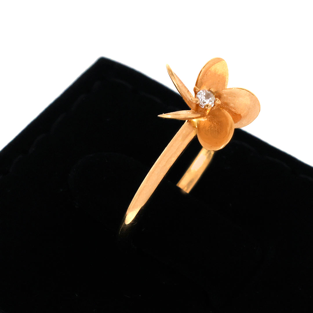 Gold flower-shaped earring with a diamond on a black background